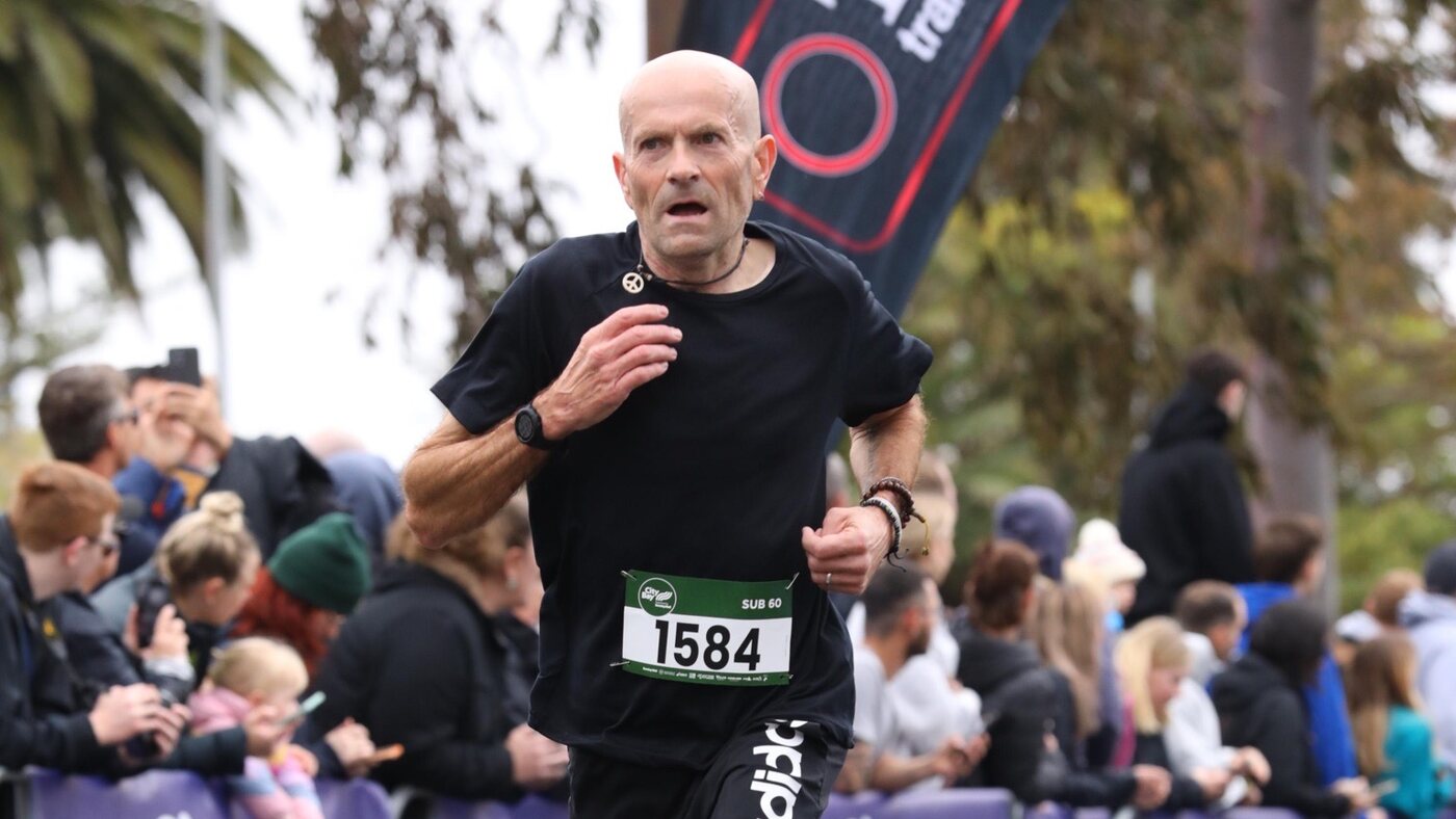 Simon Pearce running at the City-Bay, mid-stride, race number 1584.