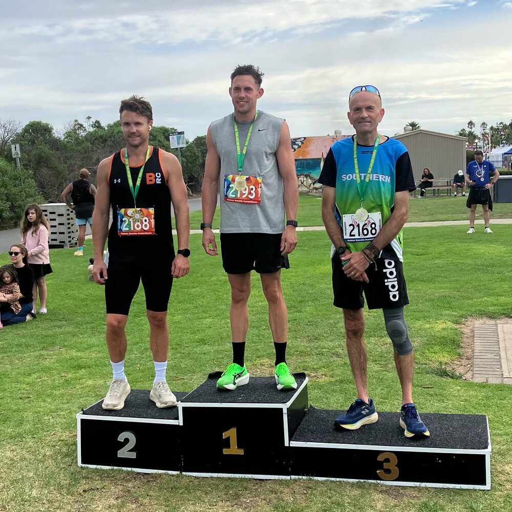 Simon standing on the third step of a race podium.