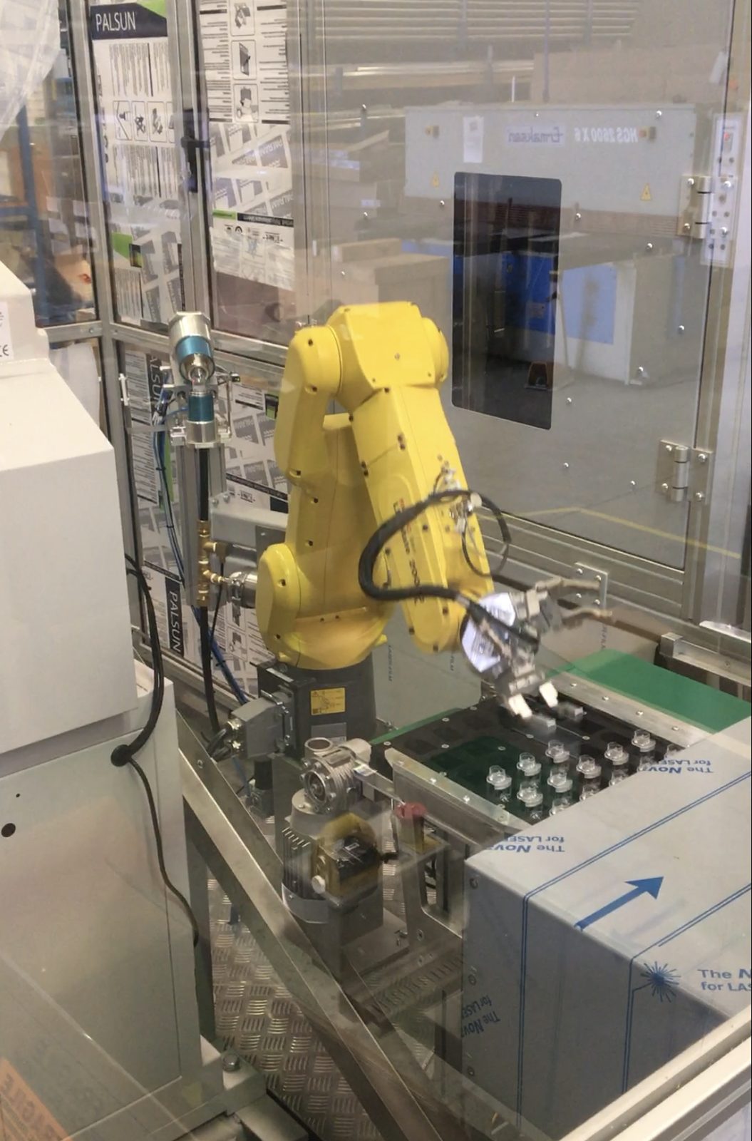 FANUC robot loading a tray of parts in an automated cell.